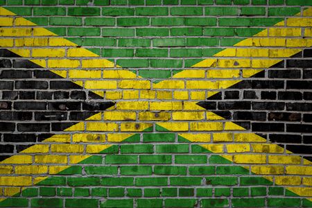 National flag of Jamaica depicting in paint colors on an old brick wall. Flag  banner on brick wall background.の写真素材