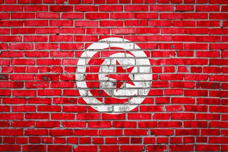 National flag of Tunisia  depicting in paint colors on an old brick wall. Flag  banner on brick wall background.の写真素材