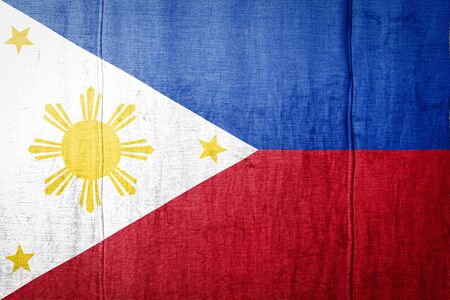 National flag of Philippines  depicting in paint colors on old clothl. Flag  banner on  fabric texture background.の写真素材