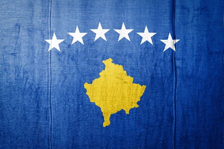 National flag of Kosovo  depicting in paint colors on old textile. Flag  banner on  fabric texture background.の写真素材