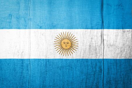 National flag of Argentina depicting in paint colors on old textile. Flag  banner on  fabric texture background.の写真素材