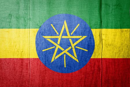 National flag of Ethiopia depicting in paint colors on old textile. Flag  banner on  fabric texture background.の写真素材