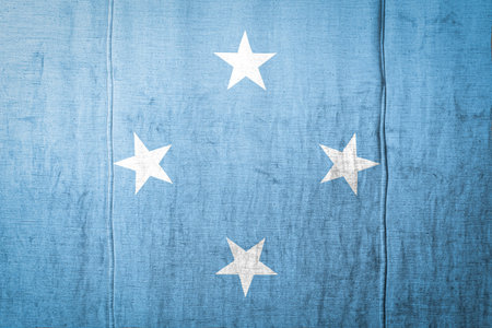 National flag of Federal States of Micronesia depicting in paint colors on old textile. Flag  banner...
