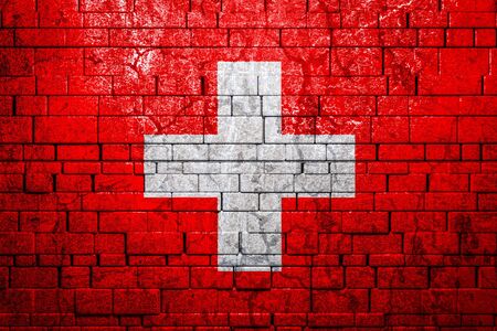 National flag of Switzerland on brick  wall background.The concept of national pride and symbol of the country. Flag  banner on  stone texture background.の写真素材