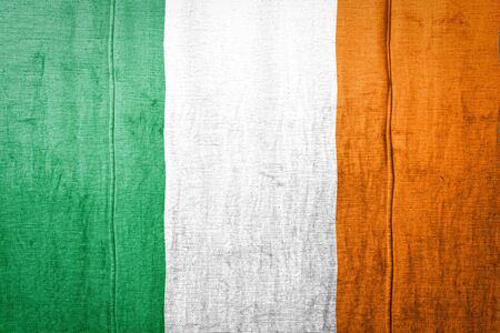 National flag of Ireland depicting in paint colors on old textile. Flag  banner on  fabric texture background.の写真素材