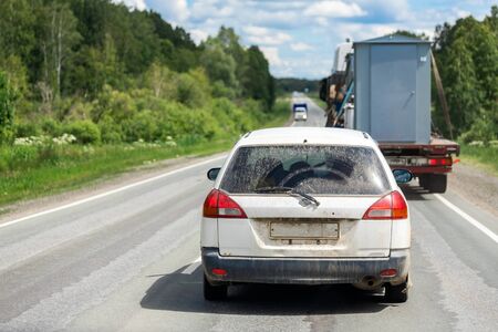 Car universal rides on an asphalt road in the background forest landscape and car traffic from trucks. The concept of moving from city to city in your car. Traveling by carの写真素材