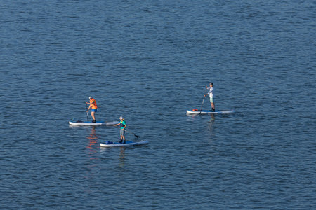 Novosibirsk / Russia - June 27 2020: Women athletes with oars swim on surfboards along the river on...