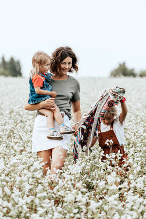 Happy family is playing, having fun on the field with flowers at sunset. Family and love concept. Young family housing conceptの写真素材