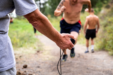 Close-up of a trainer holding a stopwatch in his hand and measuring the speed of short-distance...