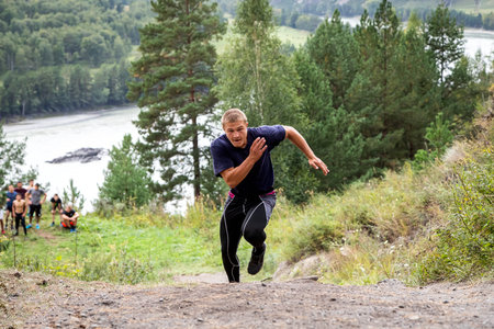 Sportsman athlete runs uphill in the background mountain river, mountains and forest. Sprint race....