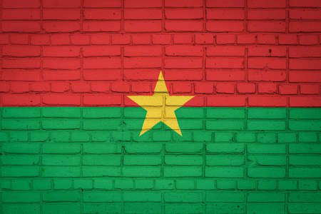 National flag of Burkino Faso depicting in paint colors on an old brick wall. Flag banner on brick wall background.の写真素材