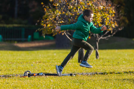 Cheerful boy play fun, run across the green field on a warm autumn day. The concept happy childhood.の写真素材