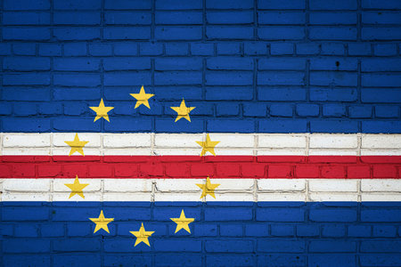 National flag of Cape Verde depicting in paint colors on an old brick wall. Flag banner on brick...