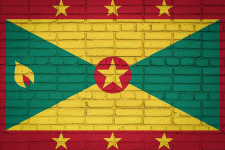 National flag of Grenada depicting in paint colors on an old brick wall. Flag banner on brick wall background.の写真素材