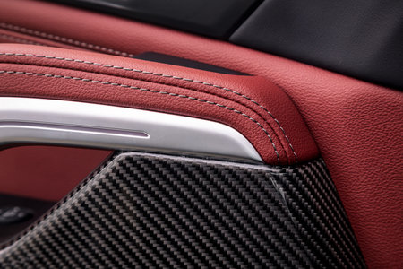 Ð¡lose up of a door control panel with chrome handle on the car door, common black and red genuine leather in a new car. Arm rest in luxury carの写真素材