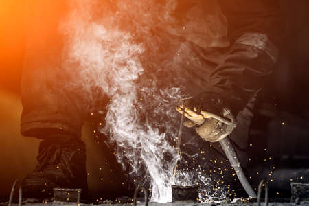 Industrial worker at a factory welding steel structure. A worker with a protective mask is welding metal using a welding machine, there is a lot of smoke aroundの写真素材