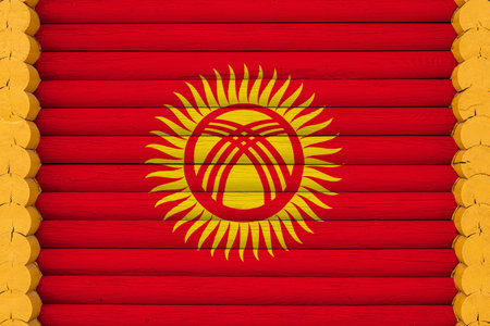 National flag of Kyrgyzstan on a wooden wall background. The concept of national pride and a symbol of the country. Flags painted on a houseの写真素材