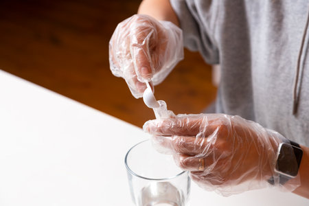 Chemistry education and training concept. Close-up woman pours a chemical solution into a test tube using a measuring spoon to create a chemical reaction. Chemical experiment on growing crystalsの写真素材