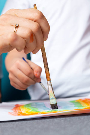 Children's creativity. mom and child son paint watercolor homework for kindergarten on blue...