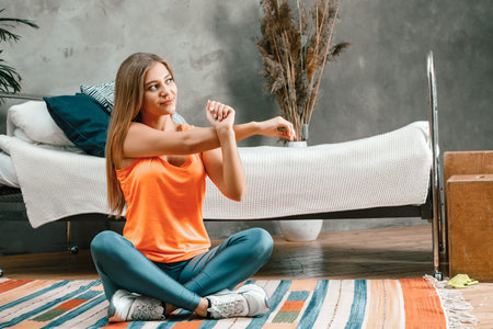 The young woman goes in for sports at home. Sporty woman with blond hair in sportwear does morning...