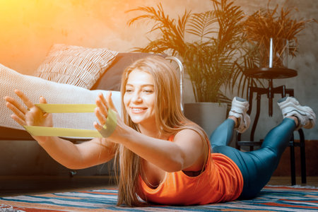 The beauty woman goes in for sports at home. Cheerful sporty woman with blond hair stretches with...
