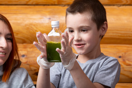 Mom and son are doing chemical experiments, watching the color change in the bottle as a result of a...