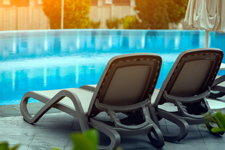 A pair of comfortable gray sun loungers set against the backdrop of a beautiful transparent pool and...