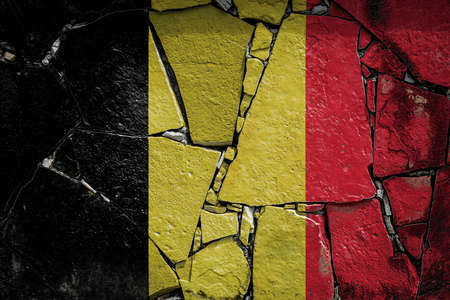 National flag of Belgium depicting in paint colors on an old stone wall. Flag banner on broken wall background.の写真素材