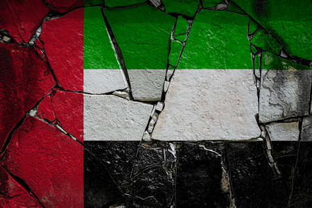 National flag of United Arab Emirates depicting in paint colors on an old stone wall. Flag banner on broken wall background.の写真素材