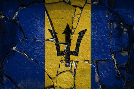 National flag of Barbados depicting in paint colors on an old stone wall. Flag banner on broken wall background.の写真素材