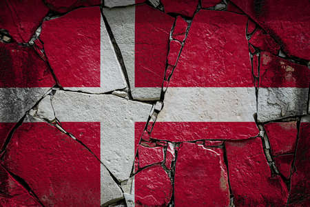 National flag of Denmark depicting in paint colors on an old stone wall. Flag banner on broken wall background.の写真素材