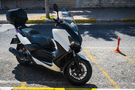 A vintage white motorcycle, moped stands in a parking against the backdrop of gray wall. Side view