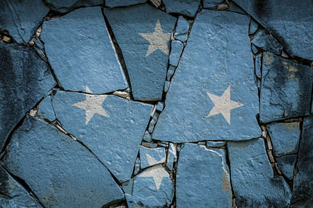 National flag of Federal States of Micronesia depicting in paint colors on an old stone wall. Flag banner on broken wall background.の写真素材