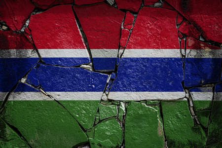 National flag of Gambia depicting in paint colors on an old stone wall. Flag banner on broken wall background.の写真素材