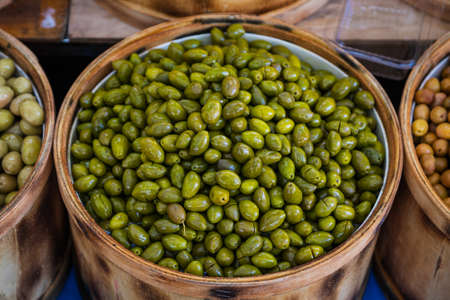 Sales of traditional products. Mediterranan olives in the market. Many bowls of olives at the farmer's marketの写真素材