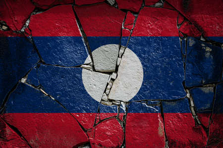 National flag of Laos depicting in paint colors on an old stone wall. Flag banner on broken wall background.の写真素材
