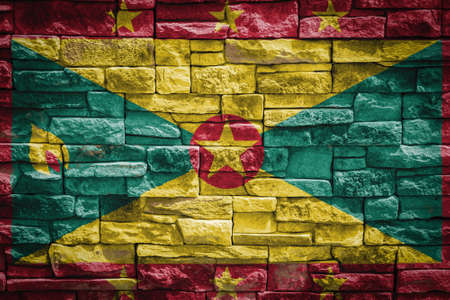 National flag of Grenada on stone wall background. The concept of national pride and symbol of the country. Flag banner on stone texture background.の写真素材