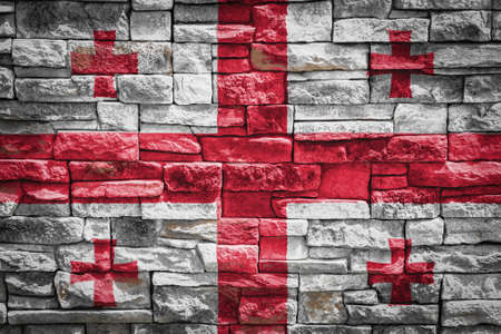 National flag of Georgia on stone wall background. The concept of national pride and symbol of the country. Flag banner on stone texture background.の写真素材
