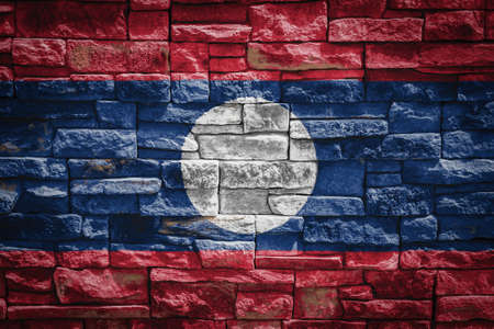 National flag of Laos on stone wall background. The concept of national pride and symbol of the country. Flag banner on stone texture background.の写真素材
