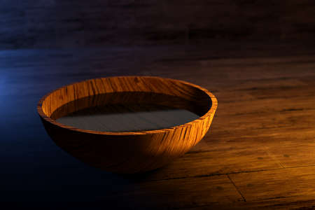 3d illustration of a round wooden bowl with water under yellow light on a dark backgroundの写真素材