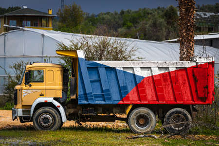 Dump truck with the image of the national flag of Czech is parked against the background of the countryside. The concept of export-import, transportation, national delivery of goodsの写真素材