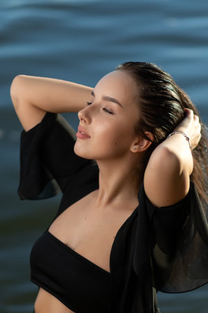 Portrait of a beautiful woman with wet hair in a sexy black bikini against the backdrop of the sea...