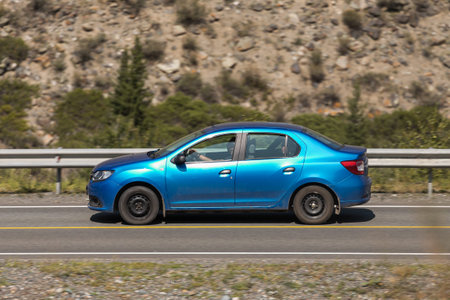 Novosibirsk, Russia - August 08, 2021: blue Renault Logan driving fast on freeway in highlands on summer day on background forestのeditorial素材