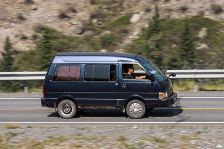 Novosibirsk, Russia - August 08, 2021: black Nissan Vanette driving fast on freeway in highlands on summer day on background forestのeditorial素材