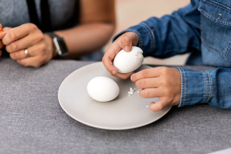 Close-up of a little boy cleaning boiled eggs at the table at Easter