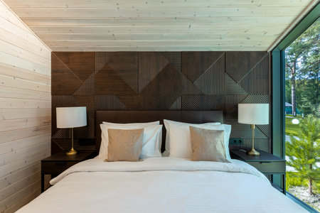 White bed, quilt and pillows in wooden bedroom. hotel bedroom. Comfortable bed with soft blanket in stylish roomの写真素材