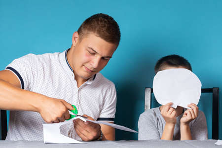 Daddy teaches the child at home, home schooling. Father helps his son do his homework, paper cutの写真素材