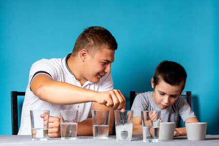 Chemistry education and study concept. Dad and her son stirs spoon the mixture into a container with chemical elements, for experiments at homeの写真素材