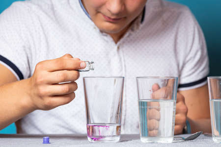 Chemistry education and training concept. Close-up of a man pour potassium permanganate into a test tube for an experiment with a change of colors, experiments at homeの写真素材