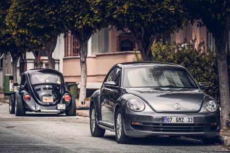 Alanya, Turkey - April 12 2021: two vintage black Volkswagen Beetle cars parked on the street in city against the backdrop of a buildung, shops, treesのeditorial素材